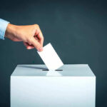 SAVE Act Shock Jolts Democrats Hand placing ballot into voting box.
