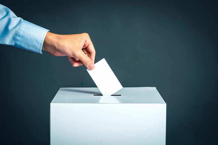 764908306 Hand placing ballot into voting box.