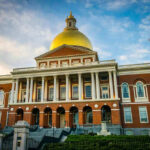 Building with golden dome and columns under a blue sky.