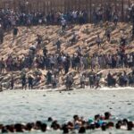 Thousands of migrants swim around the border from Morocco into Ceuta, Spain