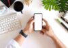 hands holding smartphone over tidy desk