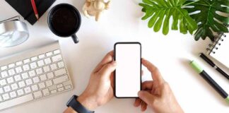 hands holding smartphone over tidy desk