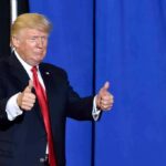 man in suit giving two thumbs up