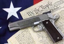 A handgun placed on top of the U.S. Constitution and an American flag