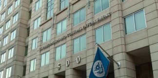 U.S. government building facade with American and blue departmental flags