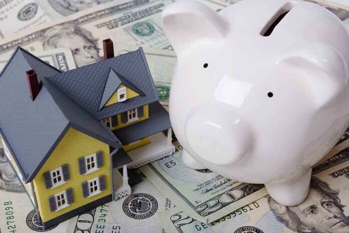 shutterstock_2018367 A model house next to a white piggy bank on a bed of dollar bills