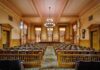 Congress Outsmarts Trump — Housing Bombshell Lands Interior view of a historic courtroom with wooden furnishings and chandeliers