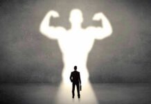 GLP-1 Shock: Lean Mass Vanishes Businessman with briefcase casts a large muscular shadow on wall