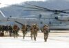 Pentagon Pays Six Figures For Military Bonuses Soldiers disembark and walk past a large military helicopter