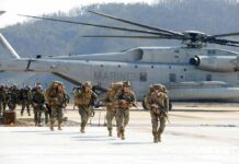 Pentagon Pays Six Figures For Military Bonuses Soldiers disembark and walk past a large military helicopter