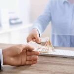 Bank teller handing euro banknotes to customer