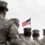 $30K Bounty Put On U.S. Troops American flag above blurred soldiers in formation