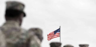 American flag above blurred soldiers in formation