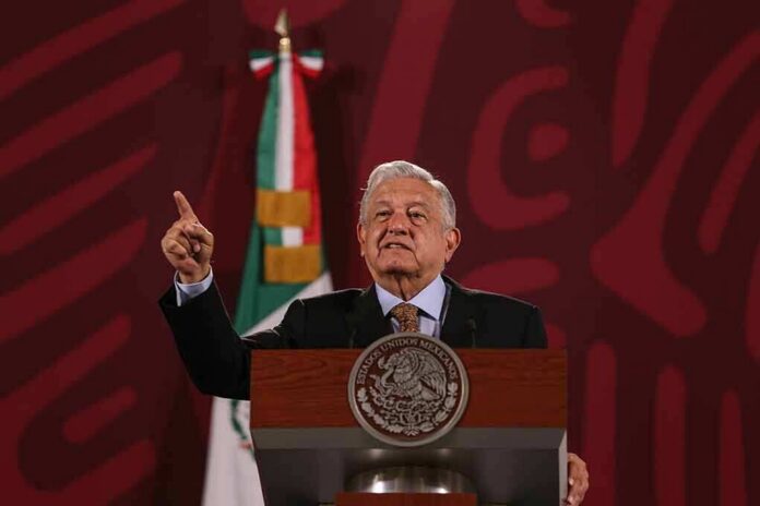 speaker at a podium gesturing with one finger raised