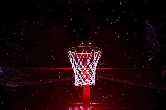 shutterstock_2496945497 Basketball hoop glowing under red spotlight