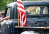 Truck Rebellion Explodes — $15B Goes Old-School American flag on the bed of a weathered vintage pickup truck