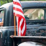 Truck Rebellion Explodes — $15B Goes Old-School American flag on the bed of a weathered vintage pickup truck
