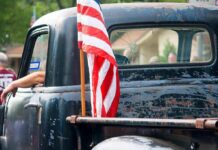 Truck Rebellion Explodes — $15B Goes Old-School American flag on the bed of a weathered vintage pickup truck