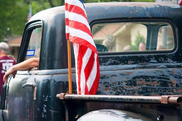 shutterstock_583065724 American flag on the bed of a weathered vintage pickup truck
