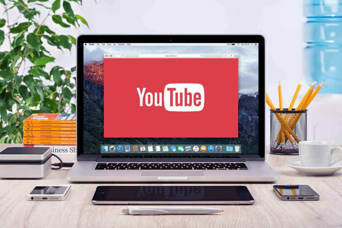 293731811-1 YouTube logo on a laptop screen on desk.