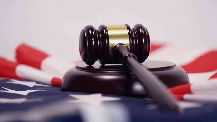shutterstock_1050534611 Judge’s gavel on a base over an American flag
