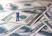 Miniature businessman standing on US dollar bills