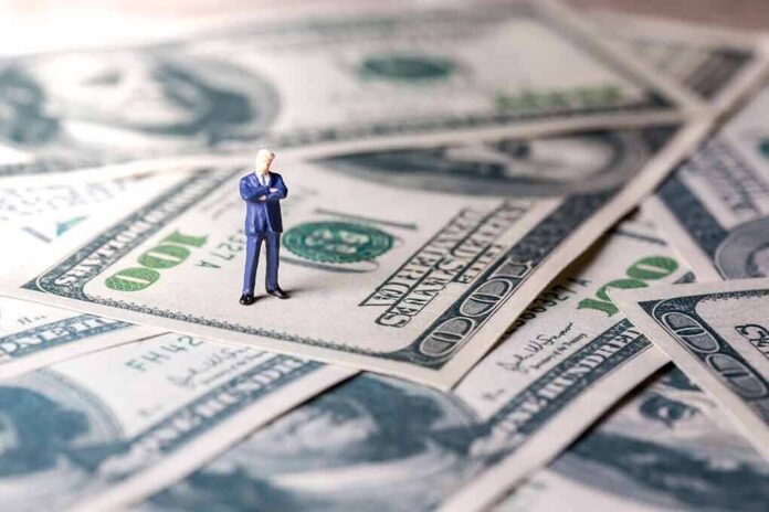 Miniature businessman standing on US dollar bills