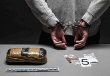 person in handcuffs behind back over table with seized packages