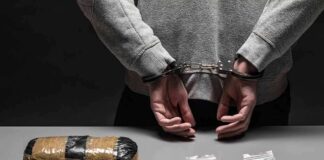person in handcuffs behind back over table with seized packages