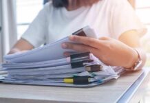 Person organizing a stack of documents with binder clips