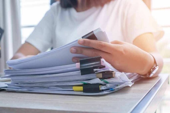 Person organizing a stack of documents with binder clips