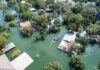 Floodwaters Deliver A Backyard Shark Aerial view of flooded neighborhood with rescue boat navigating streets