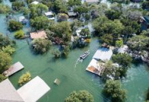 Floodwaters Deliver A Backyard Shark Aerial view of flooded neighborhood with rescue boat navigating streets