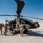 U.S. Base Hit — Troops Down Soldiers inspect a military attack helicopter on a tarmac