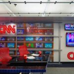 Fake News Ban Backfires – Lawsuit Erupts CNN newsroom set with red chairs and multiple TVs