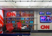 Fake News Ban Backfires – Lawsuit Erupts CNN newsroom set with red chairs and multiple TVs