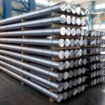 Stacked metal rods on pallets in an industrial warehouse