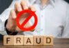 Person holding red prohibition symbol over wooden blocks spelling fraud