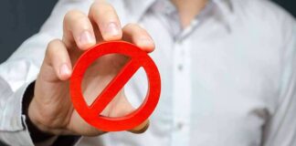 Person holding red prohibition symbol over wooden blocks spelling fraud