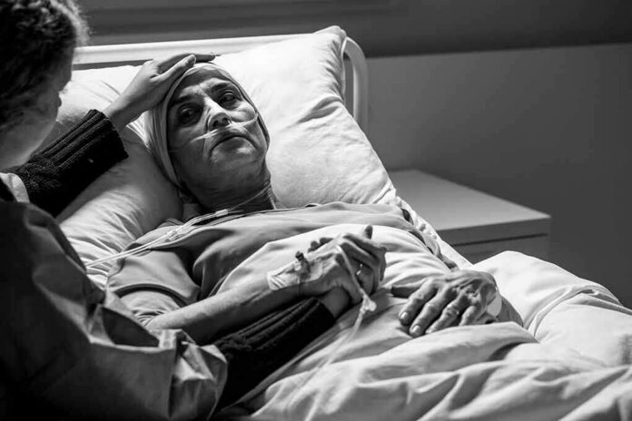 shutterstock_1677368530 Patient in hospital bed with nasal oxygen held by visitor