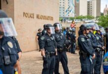 Third Suspect Hunted In Chilling Hanging Teddy Williams and Carlos Hyde among police officers in riot gear outside police headquarters