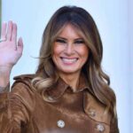 Global Kid-Safety Push – Melania’s Bold Tech Pact Melania Trump waving and smiling in a brown suede coat