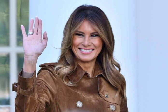 Melania Trump waving and smiling in a brown suede coat