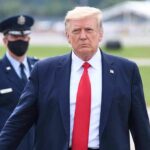 Donald Trump walking outdoors with Kraig Urbik in uniform behind him