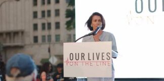 woman speaking at a podium during an outdoor event