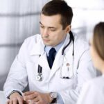 Doctors in white coats discuss patient case at a table