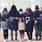 Sorority Power Play Stuns Courts Group of women standing arm in arm with purple ribbons