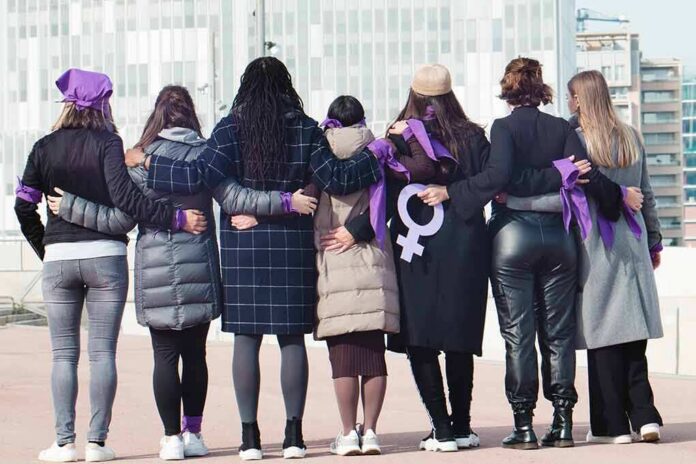 shutterstock_2103713153 Group of women standing arm in arm with purple ribbons