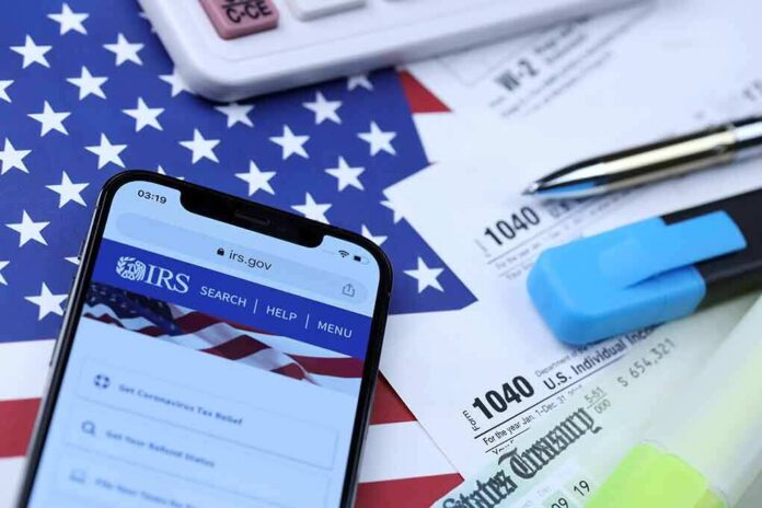Smartphone showing IRS website on top of tax forms and office supplies