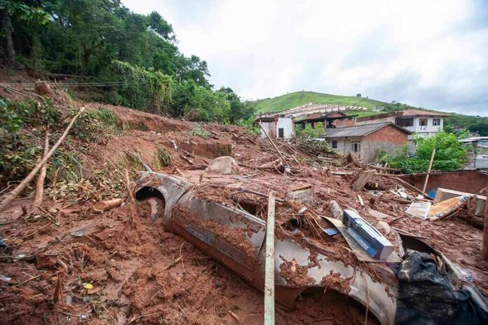 shutterstock_2124385472 Landslide debris covering houses and a buried car on a muddy hillside